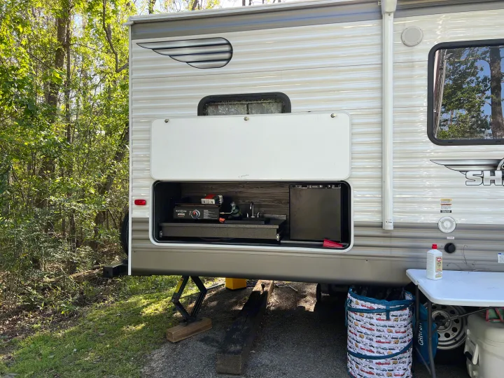 This RV rental features a convenient outdoor kitchen with a griddle, sink, and fridge, ideal for campsite cooking.. Shasta 25RS 2021
