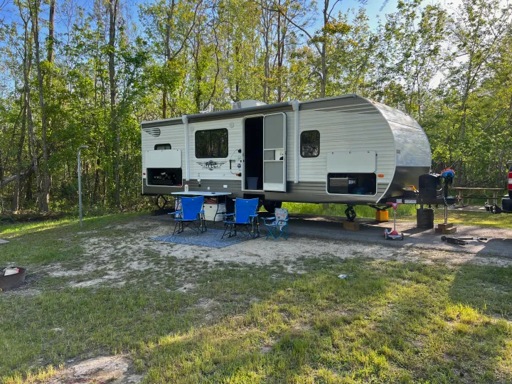 A travel trailer RV rental perfectly set up at a wooded campsite, offering a relaxing outdoor retreat.. Shasta 25RS 2021
