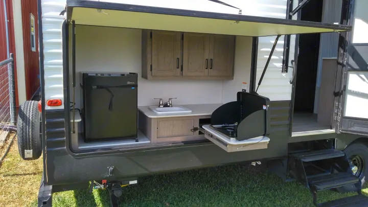 RV rental with a convenient outdoor kitchen featuring a fridge, sink, and pull-out stove, perfect for camping.. Keystone Hideout 2021