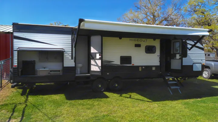 This RV rental features a large travel trailer with an extended awning and outdoor kitchen, perfect for camping adventures.. Keystone Hideout 2021