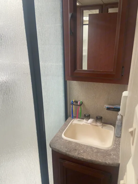 RV rental bathroom: a small sink area with toothbrushes, soap, and frosted shower door.. Palomino Puma 2015