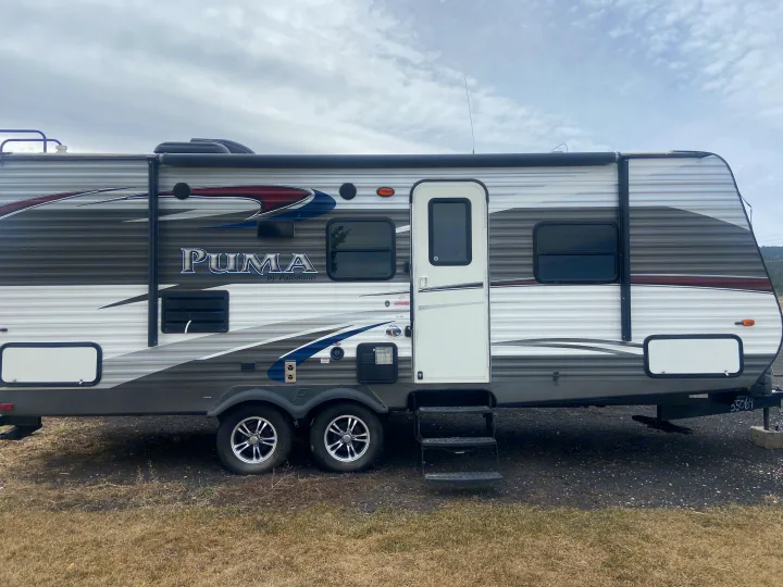 RV rental: PUMA by Palomino travel trailer, parked on grass under a cloudy sky.. Palomino Puma 2015