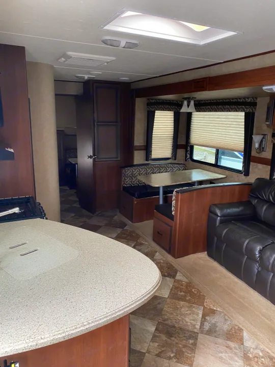 Bright RV rental interior: kitchen counter, dining booth, sofa, and skylight visible. Perfect for road trips!. Crossroads RV Zinger 2015