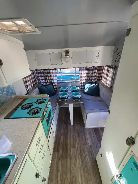 Experience a charming rv rental! This retro camper features a teal kitchen, set dinette, & checkered curtains for cozy trips.. Shasta 1500 1956