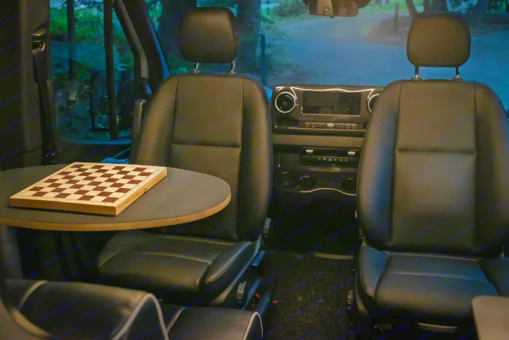 RV rental interior: a chessboard on a table between comfortable black seats, perfect for relaxation on your journey.. Winnebago Revel 2022