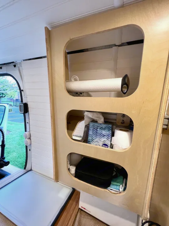 Organized interior of an RV rental. A wooden cabinet features open storage for paper towels, tissues, and toiletries.. Mercedes-benz Sprinter 2016