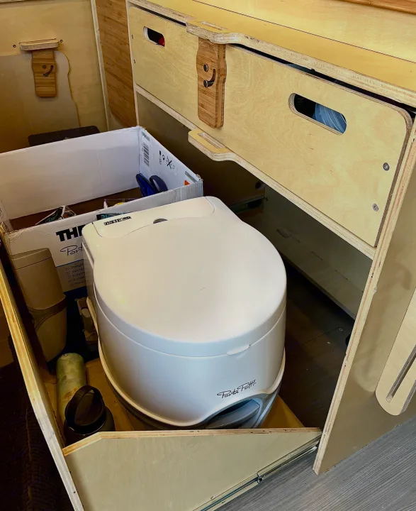 RV rental interior with a white Porta Potti portable toilet, custom wood drawers, and clever compact storage solutions.. Mercedes-benz Sprinter 2016