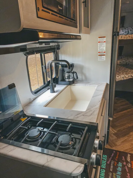 Compact RV rental kitchen with stove, sink, coffee maker, and microwave, ideal for camping adventures.. Forest River Other 2022