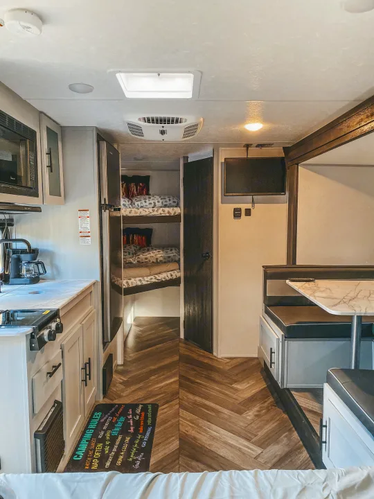 Inside a spacious RV rental: kitchen, bunk beds, dinette, and herringbone flooring for comfortable camping trips.. Forest River Other 2022