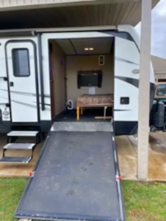 This RV rental features an open rear ramp leading to a versatile "toy hauler" space inside, complete with a TV and bench.. Keystone Outback 2018