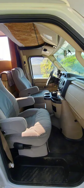 Step inside this RV rental! View of the front cockpit with light grey captain's chairs, dashboard, and steering wheel.. Jamboree Jamboree Motorhome 2011