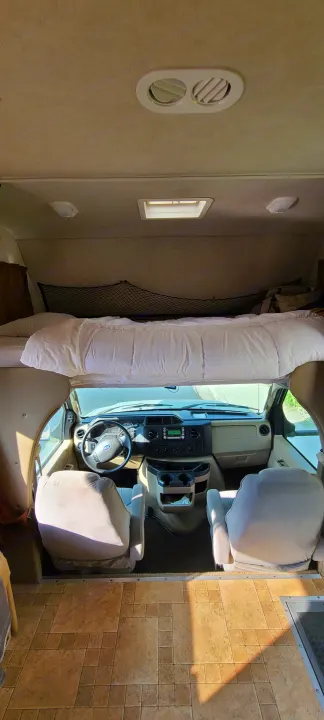 Inside a spacious RV rental, viewing the front cabin, comfy overhead bed, and light-toned tile floor.. Jamboree Jamboree Motorhome 2011
