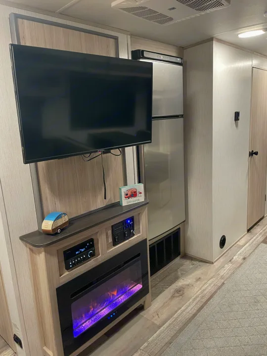 Spacious RV rental interior featuring a TV, electric fireplace, and full-size fridge for a comfortable journey.. Heartland Sundance 294BH 2022