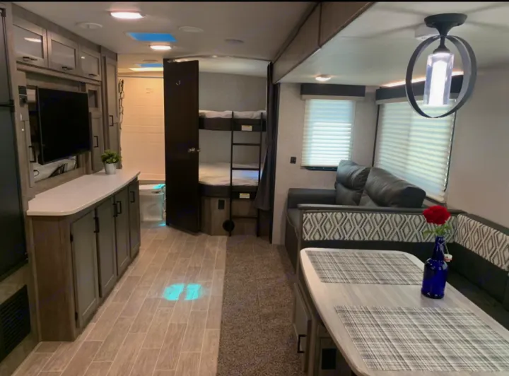 Spacious RV rental with comfy living area, dinette, kitchen, bunk beds, and bathroom visible through open doors.. Heartland Wilderness 2020