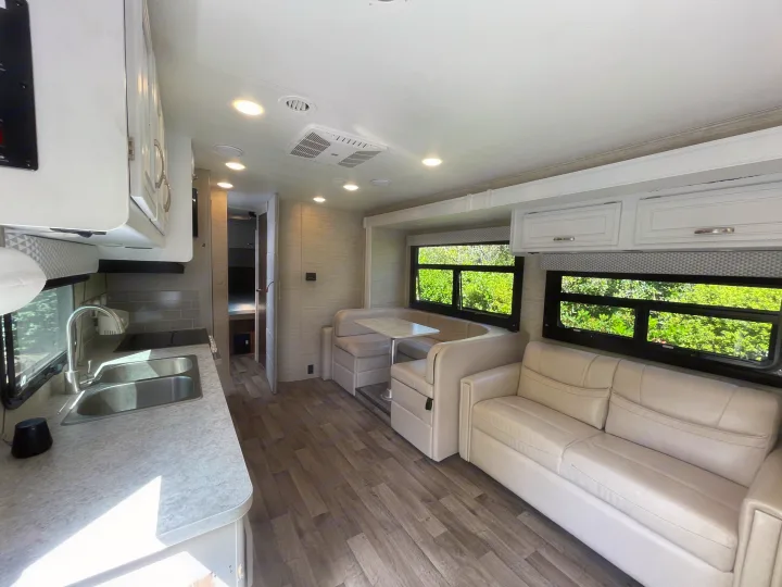 Bright and spacious RV rental interior showcasing a full kitchen, dining booth, and comfortable living area.. Jayco Redhawk 2021