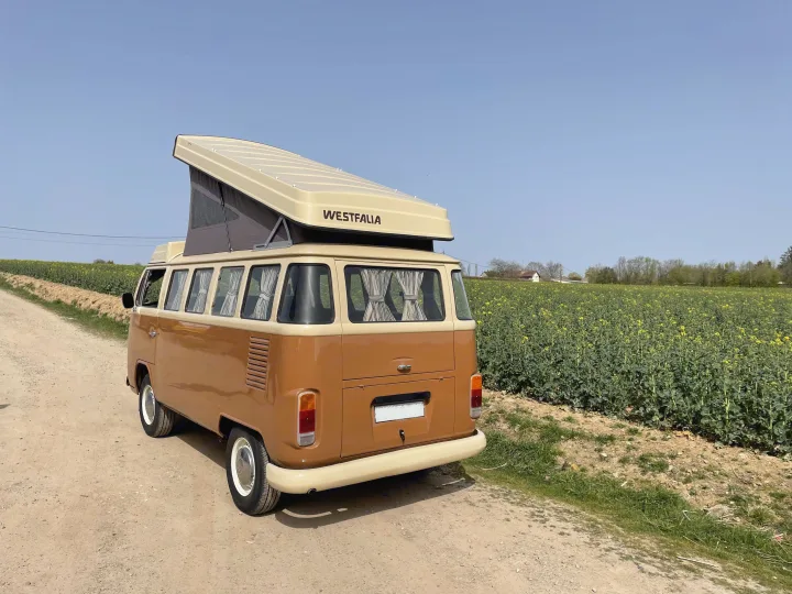 Classic two-tone VW Westfalia camper with pop-top, parked by fields. Perfect for your next RV rental road trip.. Volkswagen westfalia 1983