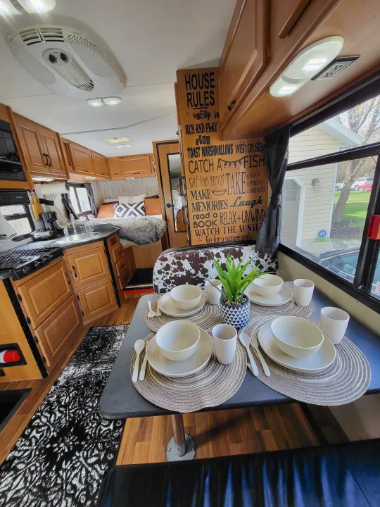 This RV rental's cozy interior showcases a set dining table, compact kitchen, and bedroom, ideal for adventures.. Thor Majestic 2014