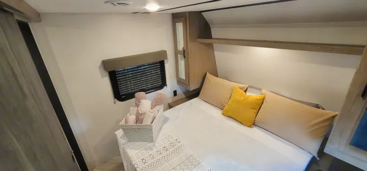 Cozy RV rental bedroom featuring a comfortable bed, practical overhead storage, and a window for scenic views.. Keystone RV Hideout Luxury Edition 2021