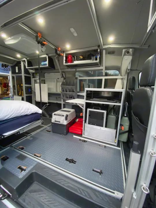 Modern rv rental interior: bed, Dometic cooler, ample modular storage, and diamond plate floor for adventure.. vandoit DO 2018