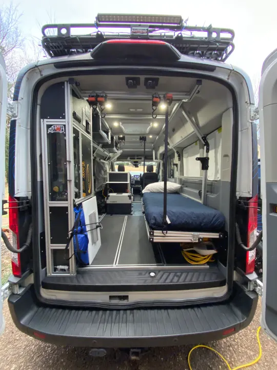 Detailed view of a versatile RV rental camper van's rear interior, featuring a bed, organized storage, and utility gear.. vandoit DO 2018