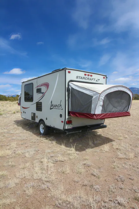 Starcraft Launch RV rental camper parked in a dry, open field with its pop-out tent deployed, ready for camping adventures.. Starcraft Launch 2016