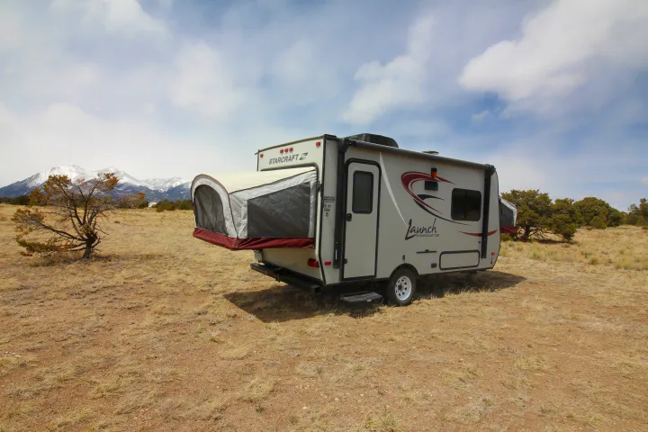 RV rental: A Starcraft Launch camper with an extended bed is parked in a dry field, with snow-capped mountains in the distance. Ideal for adventures.. Starcraft Launch 2016