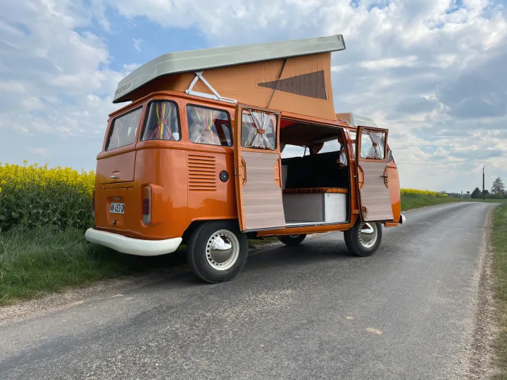 This vibrant orange vintage VW Westfalia camper, perfect for an RV rental trip, shows its open pop-top & interior.. Volkswagen westfalia 1984