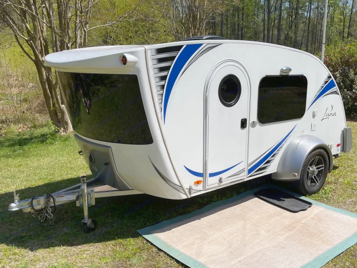 Modern white teardrop camper, a great RV rental option, with blue graphics and tinted windows, sits ready on green grass.. InTech RV InTech RV Trailer 2018