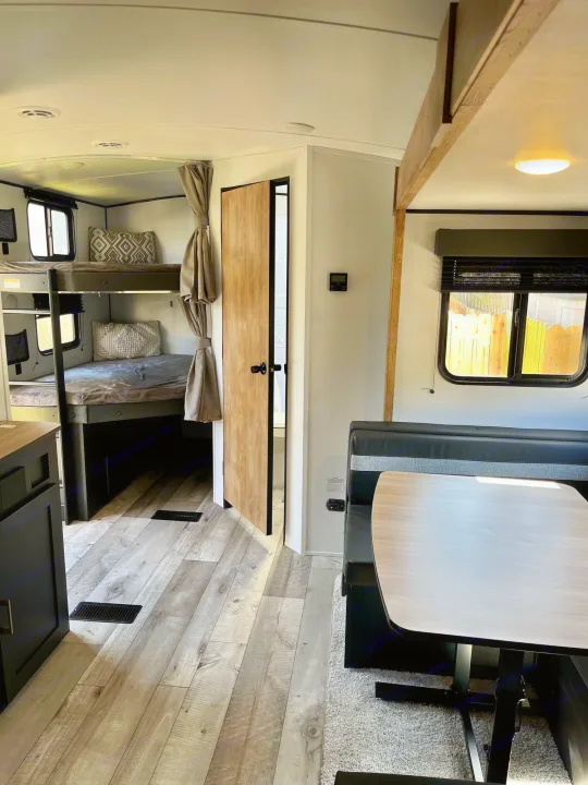 This RV rental interior features a cozy dinette and practical bunk beds, ideal for family adventures in a travel trailer.. Springdale 251bh 2022