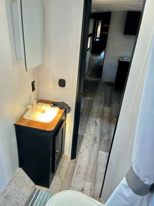 Compact RV rental bathroom with sink, vanity, and view into the bedroom. Modern design for comfortable travel.. Springdale 251bh 2022