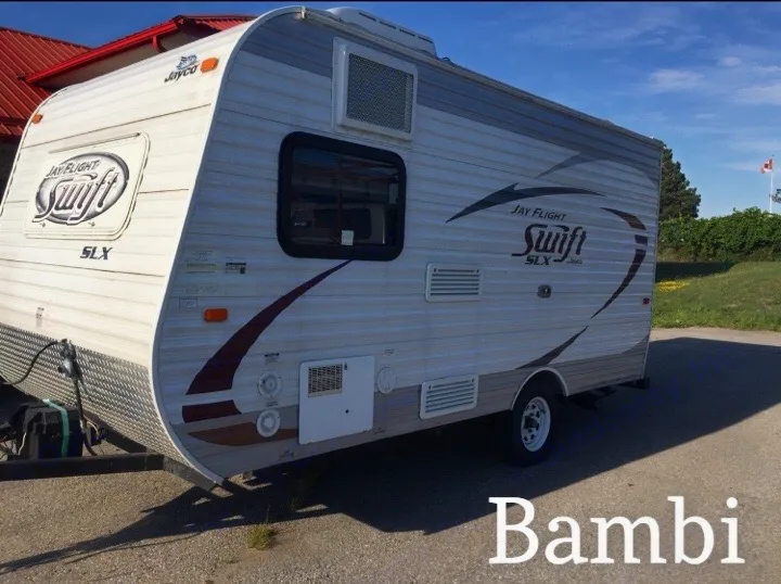 A white and grey Jayco Jay Flight Swift SLX travel trailer, ideal for an rv rental, parked on asphalt under blue skies.. Jayco Bambi 2014
