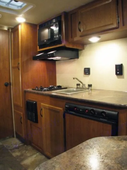 Inside an RV rental, a well-equipped kitchen features a microwave, stove, sink, and refrigerator. Perfect for road trips.. Jayco Bambi 2014
