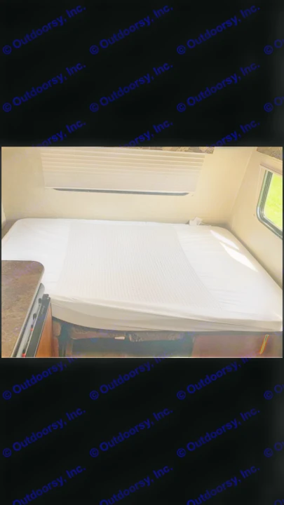 Comfortable RV rental sleeping area with fresh white linens and window blinds, perfect for your next travel adventure.. Jayco Bambi 2014