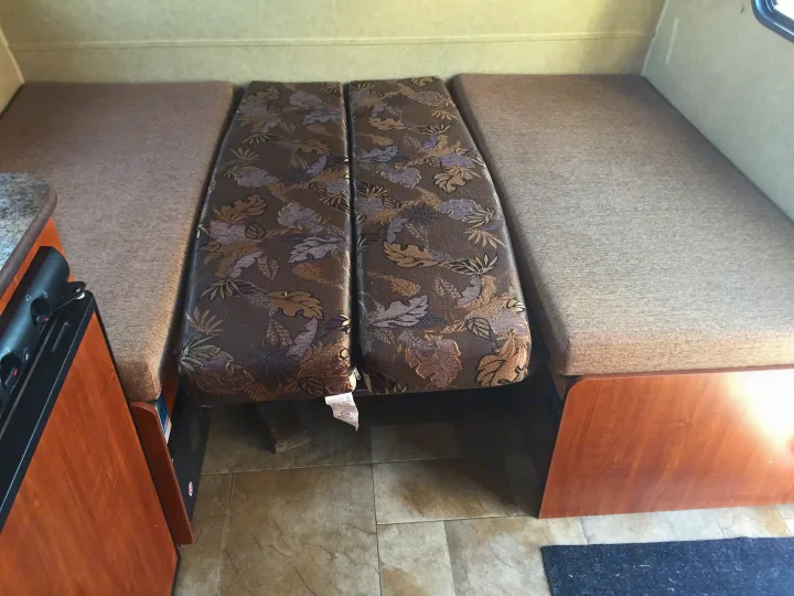 This RV rental's versatile dinette area features light upholstered bench seats and patterned cushions, easily converting for sleeping.. Jayco Bambi 2014