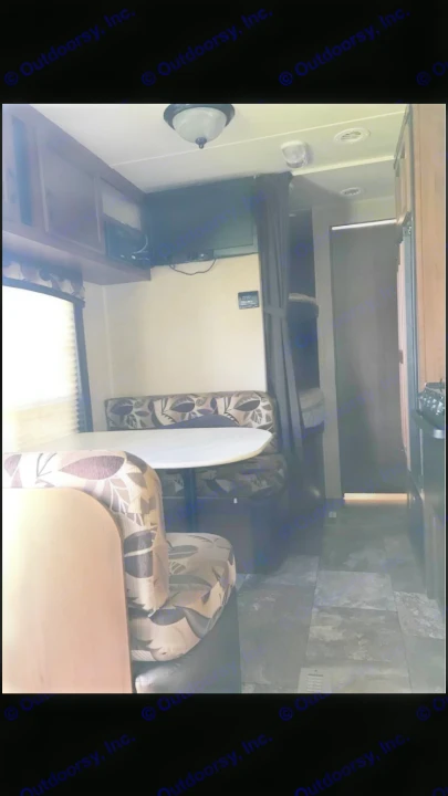 A cozy RV rental interior with a dinette, wall-mounted TV, bunk beds, wood cabinets, and tiled floor.. Jayco Coyote 2014