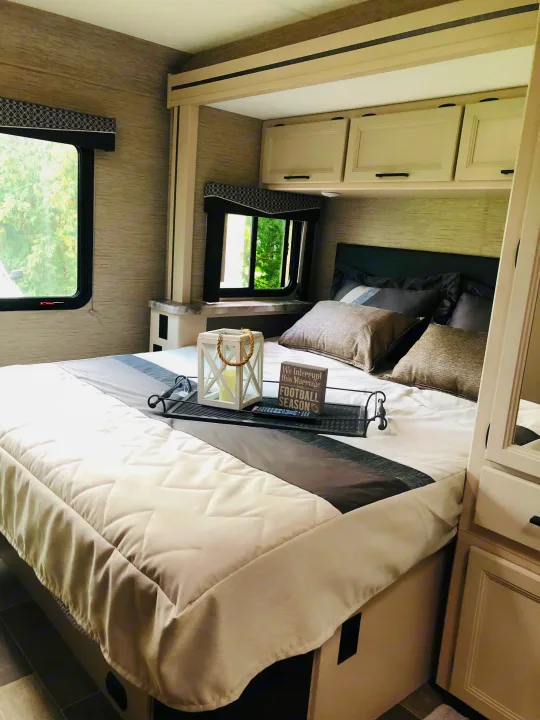 Spacious and modern RV bedroom interior, ideal for your next RV rental. Features a comfy bed, storage, and natural light.. Thor Chateau 2022