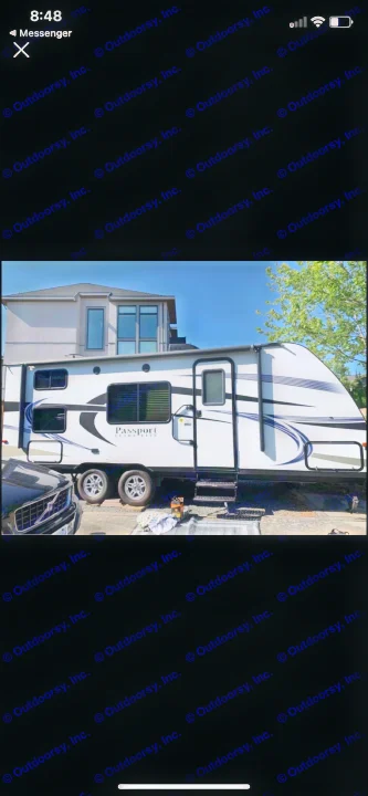 This white 'Passport Ultra-Lite' travel trailer for RV rental, parked outdoors on a sunny day.. Keystone Passport 2017