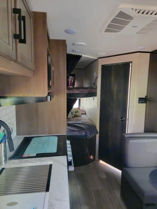 Inside this modern RV rental, find a compact kitchen with stove and sink, comfortable bunk beds, and an efficient AC unit.. Jayco Rocky Mountain Edition 2022