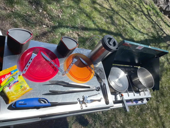 RV rental outdoor kitchen setup: A table with a propane stove, pots, plates, utensils, and coffee press ready for camping meals.. Toyota 4Runner 2021
