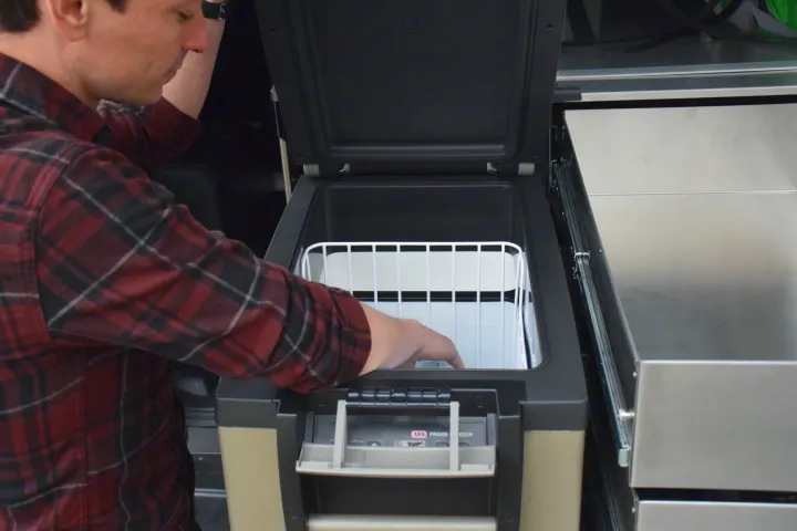 Man reaches into an ARB portable fridge/freezer, perfect for an RV rental. Essential gear for camping adventures.. Toyota 4Runner 2021