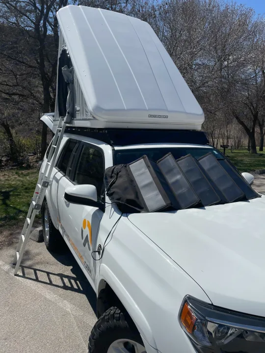 This white overland SUV with an open rooftop tent and solar panel is ready for your next rv rental adventure.. Toyota 4Runner 2021