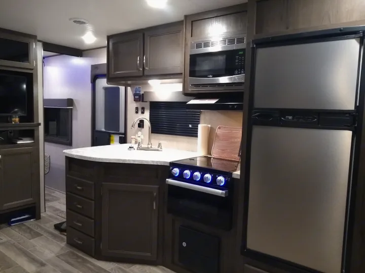 Modern RV rental interior: well-equipped kitchen with stainless steel appliances and ample dark wood cabinetry.. Jayco Jay Flight SLX 2021