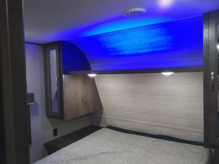 Cozy RV rental bedroom featuring modern blue LED lighting, comfy bed, and built-in storage.. Jayco Jay Flight SLX 2021