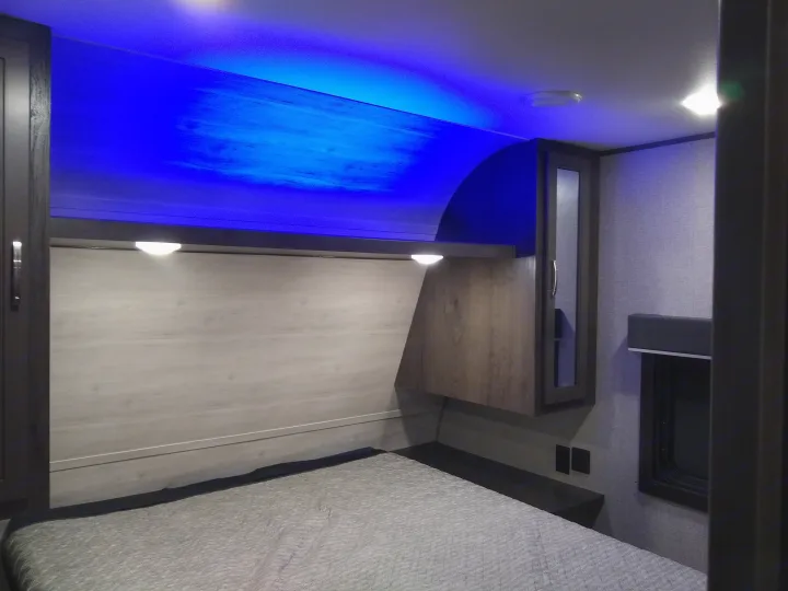Experience comfort in this modern RV rental bedroom with ambient blue lighting, a cozy bed, and practical storage.. Jayco Jay Flight SLX 2021