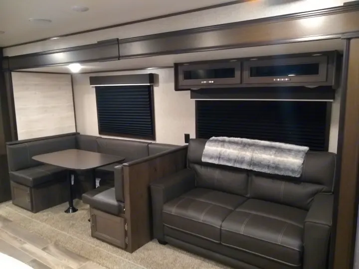 Inside an RV rental: a modern living space featuring a comfortable dinette, sofa, and overhead cabinets.. Jayco Jay Flight SLX 2021