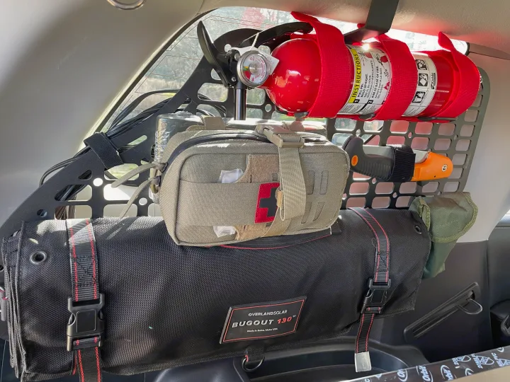 Inside an rv rental, a trunk storage panel holds a fire extinguisher, first-aid kit, and Overlandsolar Bugout gear for vehicle preparedness.. Toyota 4Runner 2021
