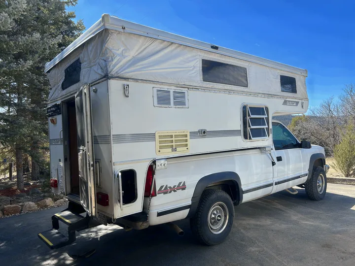 This white pop-up truck camper on a pickup is ready for your RV rental camping adventure.. Chevrolet Open Road 1998