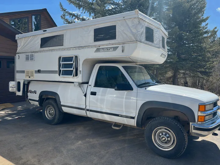 This white 4x4 pickup truck with a pop-up LITE-CRAFT truck camper is ready for your next RV rental adventure.. Chevrolet Open Road 1998