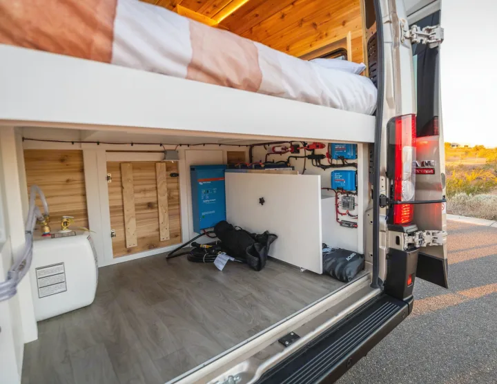 RV rental: Organized rear storage of a camper van with a bed above, featuring a Victron electrical system and water heater.. Dodge Ram Promaster 2500 High Roof 159" 2021