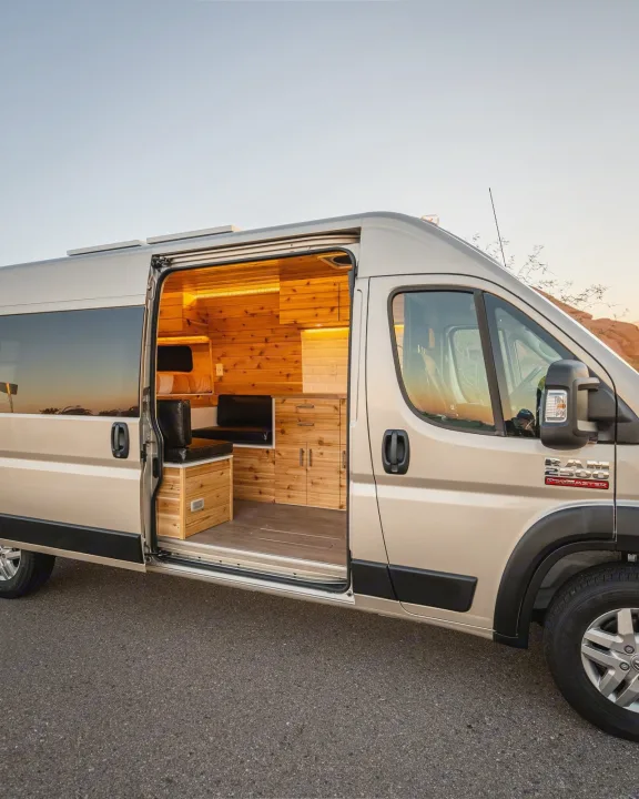 Golden Ram ProMaster rv rental opens to reveal a custom wooden interior with kitchen & bed, ideal for adventure.. Dodge Ram Promaster 2500 High Roof 159" 2021